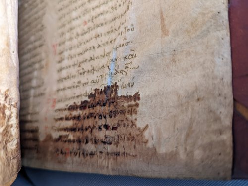 Manuscript with water damage on the button. The text is in two columns and the water damage reaches up 5 or 6 lines.