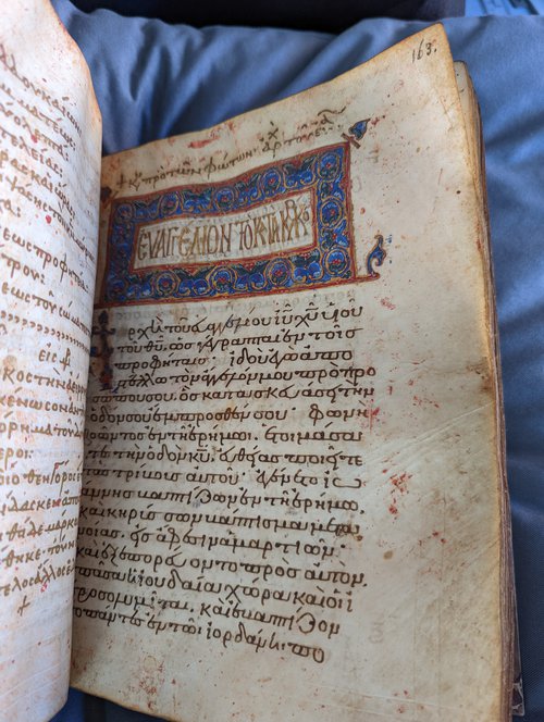 Manuscript Page with Ornate Heading. The heading has blue backfilling with gold and red accents and swirls.